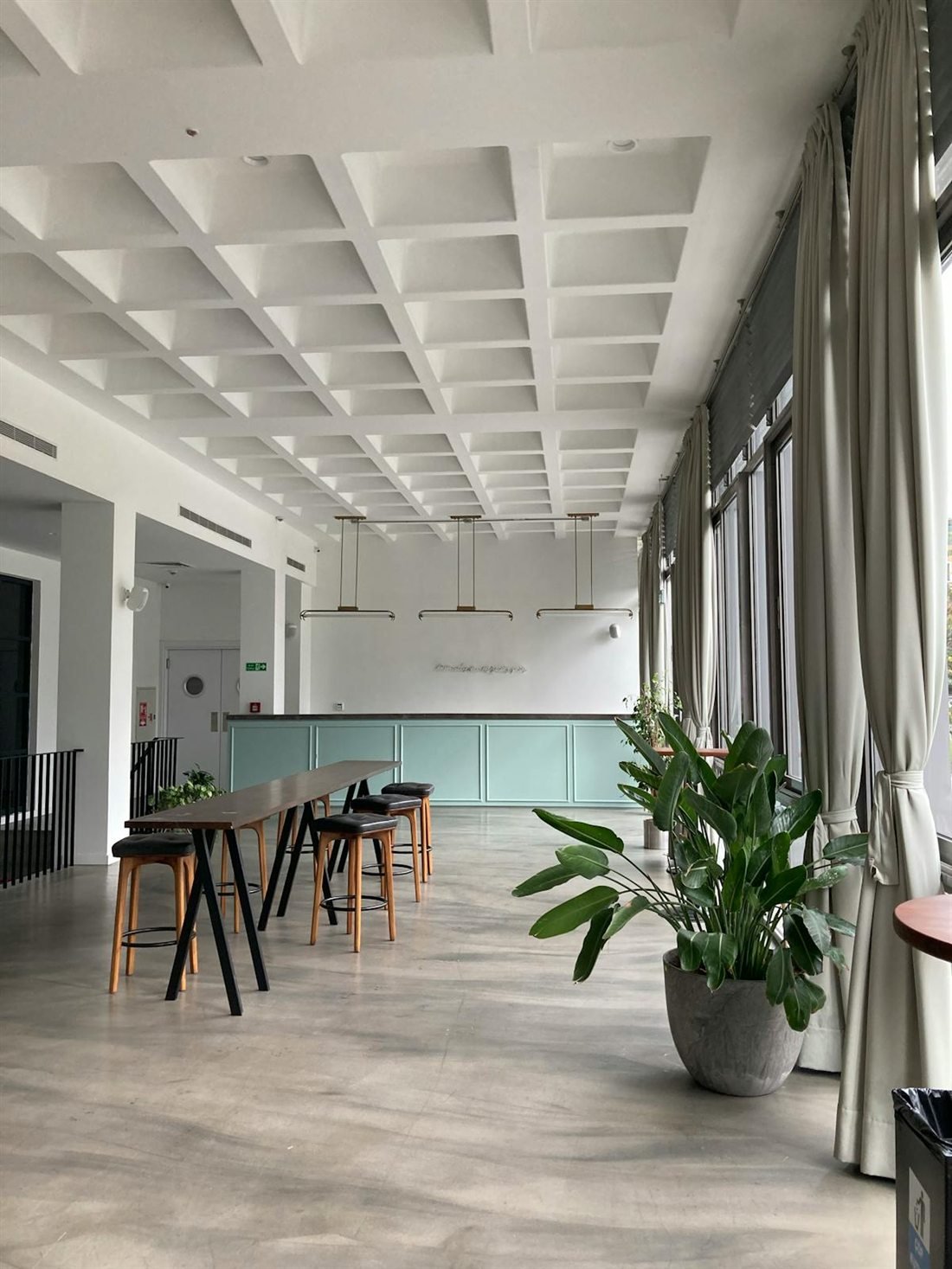 Lo spazio ToPlay: un interno luminoso con tavolo alto, sgabelli in legno e una grande pianta
